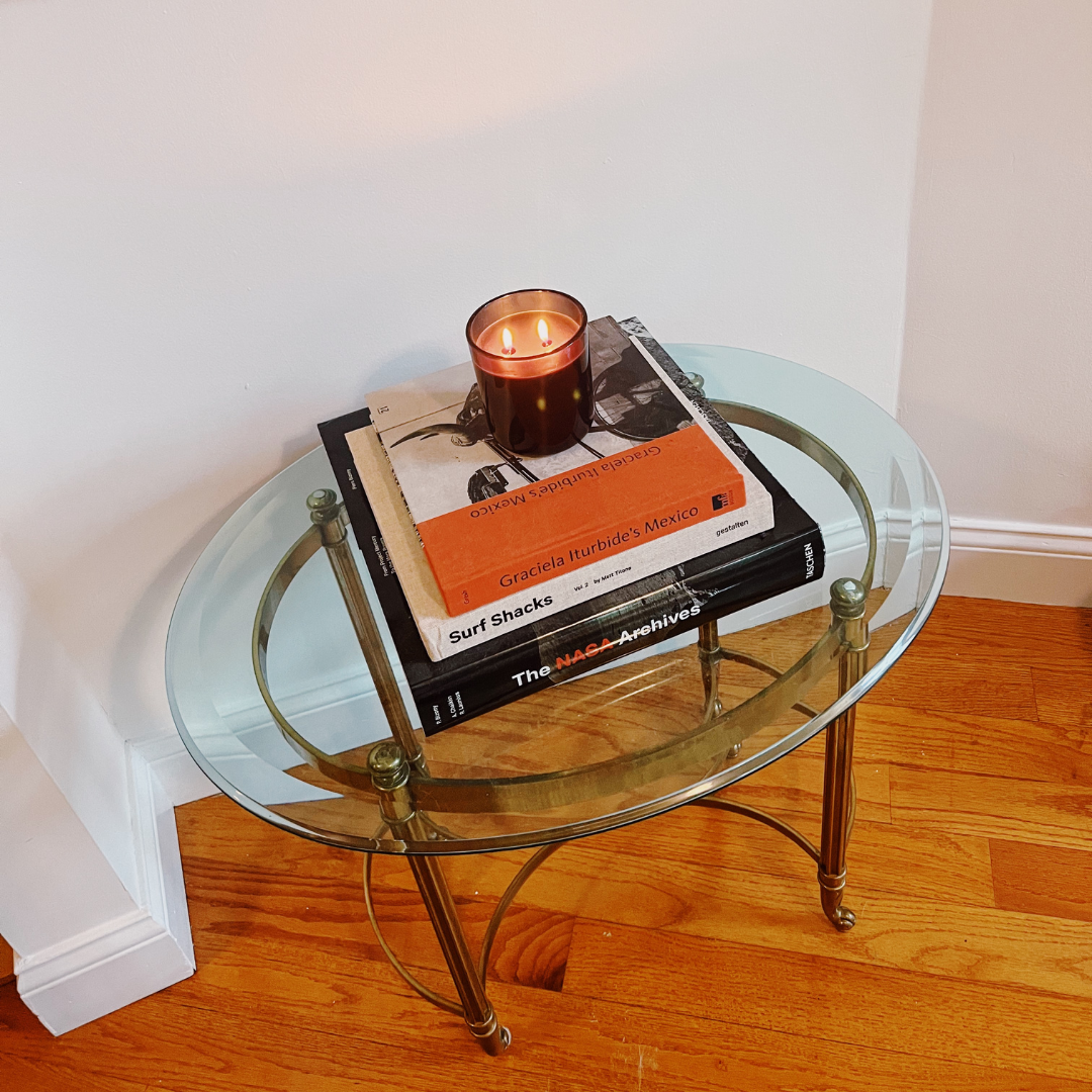lit candle in black glass vessel on side table. living room decor