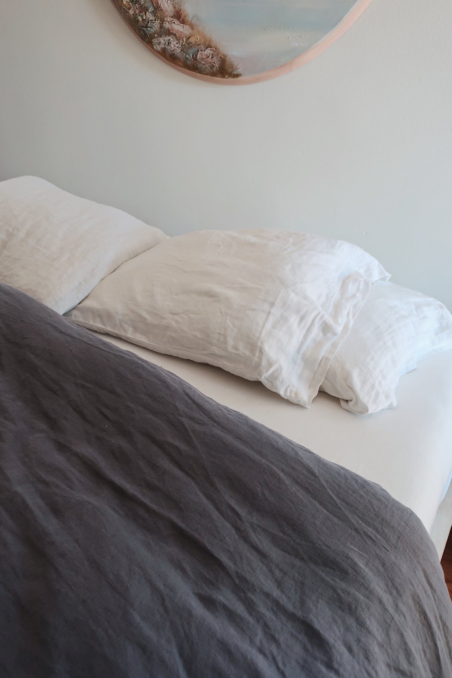 bed with hemp bedding. white pillowcases and fitted sheet and a navy duvet cover