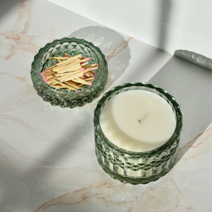 candle shown from above. holiday candle in mint colored antique-style chunky glass vessel. candle lid filled with matchsticks.